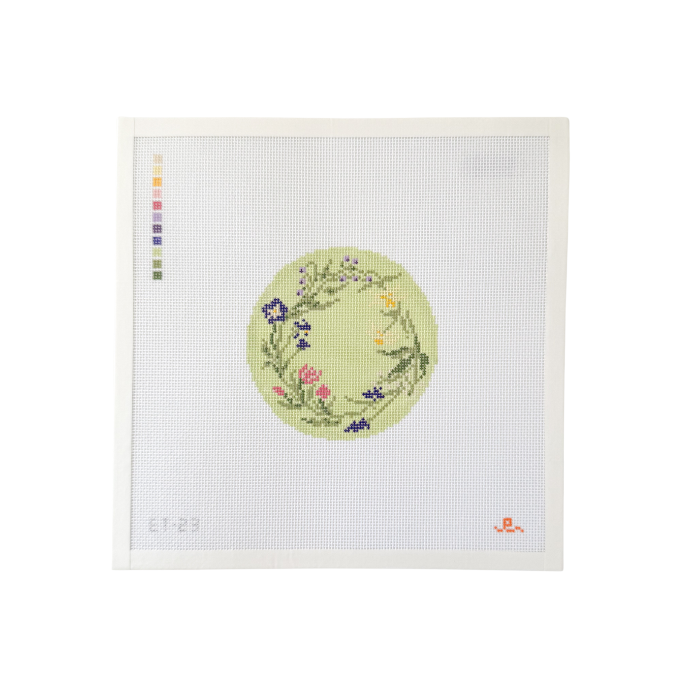 white square shaped needlepoint canvas with light green circular design with a wreath of spring flowers