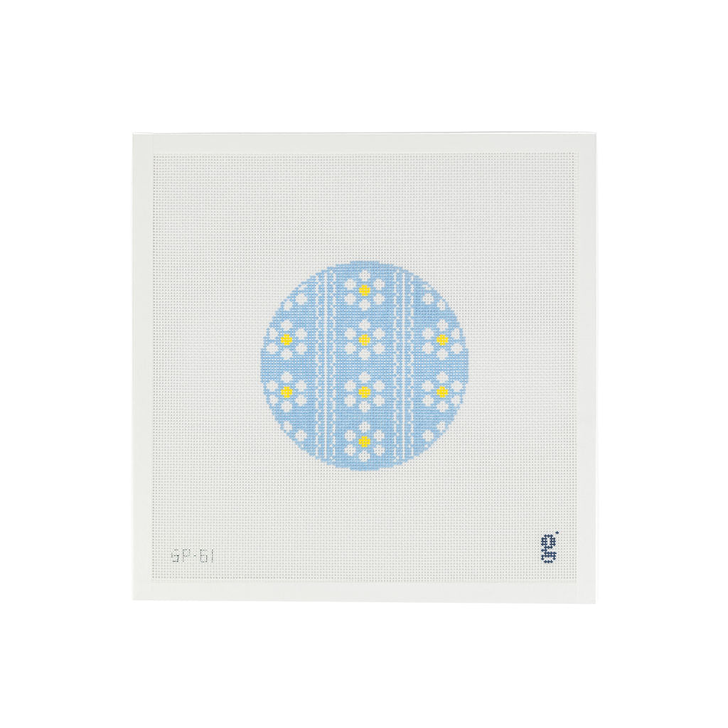 White needlepoint canvas with a light blue circular design at center with white and yellow daisy flowers and two vertical scallop stripes
