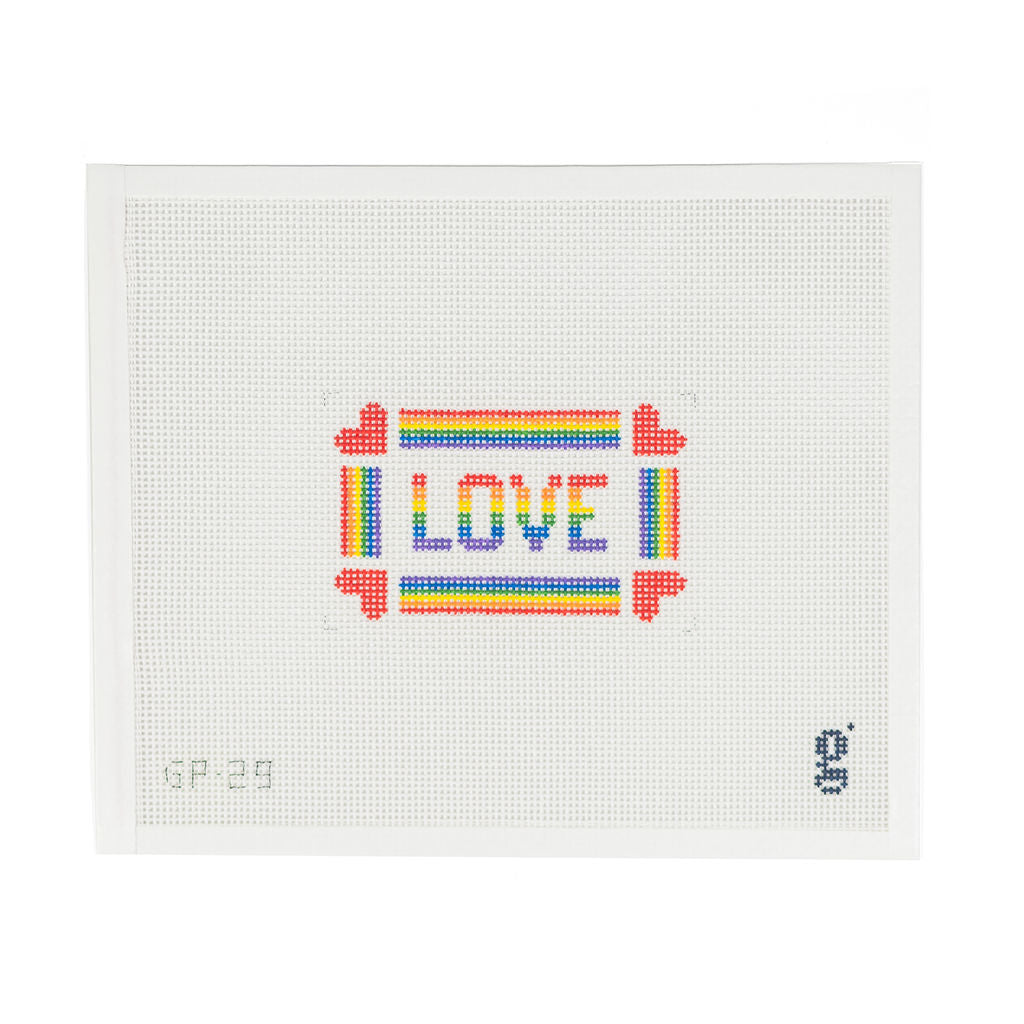 white needlepoint canvas with the word LOVE written in rainbow block text surrounded by rainbow striped border with a red heart at each corner 