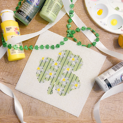 white square shaped needlepoint canvas with light green 3 leaf clover with white and gray daisy pattern on top