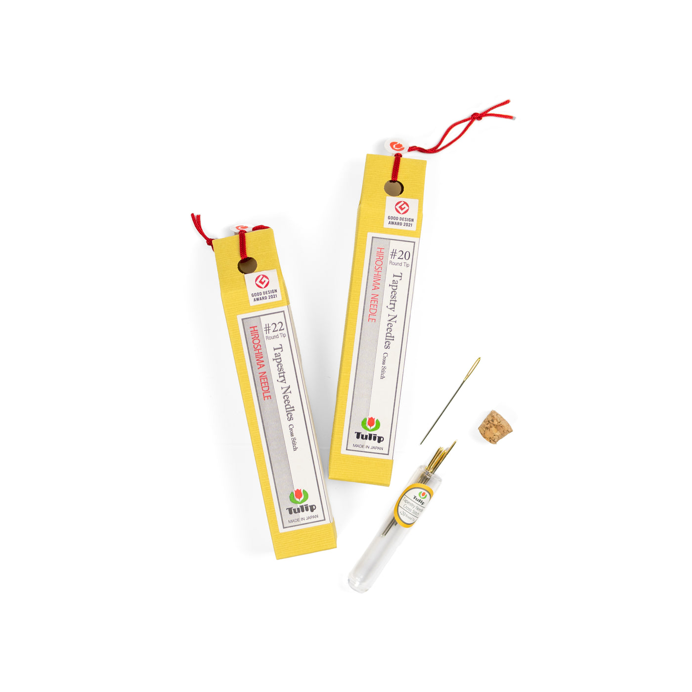 Yellow boxes with red tie at the top and printed sticker labels noting needle size and brand. To the right of the two boxes is an open tube of needles with a cork top.